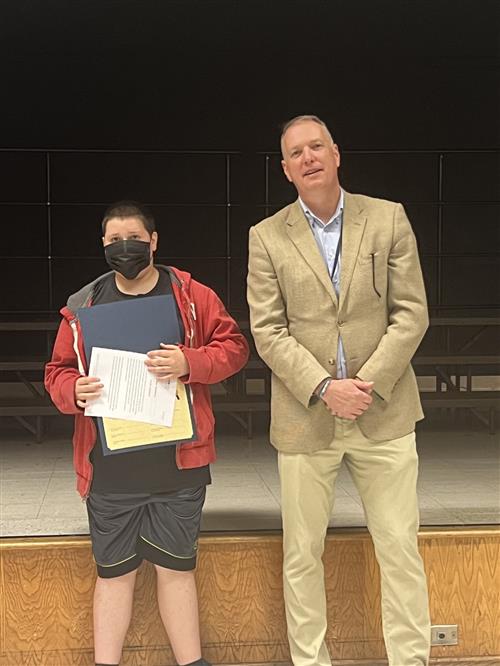 Blake B. poses with his award and the District Superintendent.